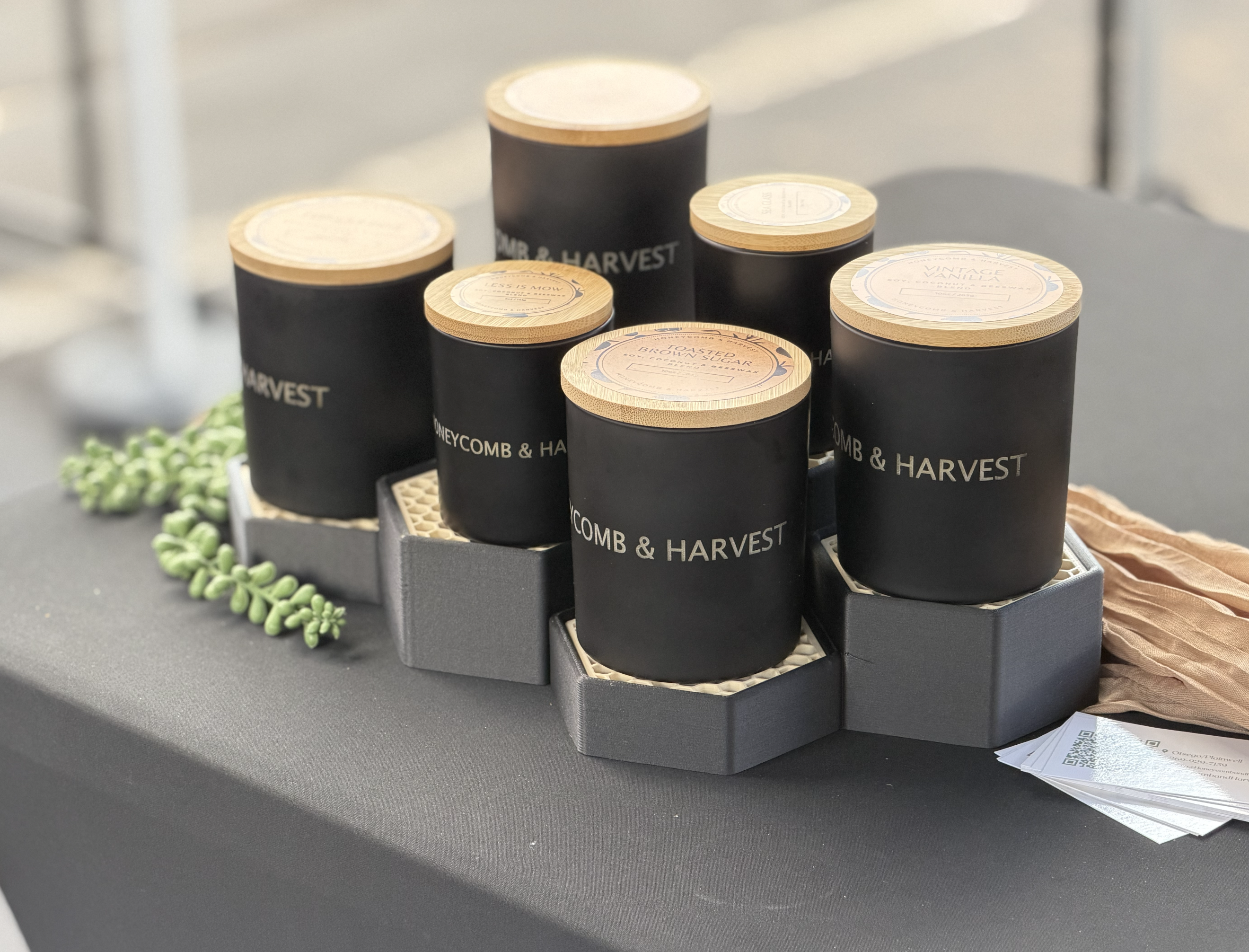 Honeycomb & Harvest candles displayed on custom black hexagonal display stands